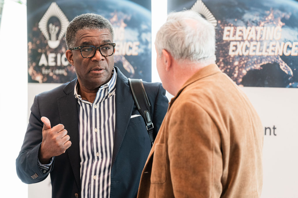 AEIC members networking beside the Elevating Excellence backdrop